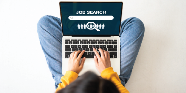 A woman types on a laptop open to a page reading &apos;job search&apos;.
