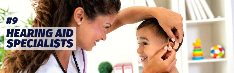 A medical worker adjusts a hearing aid for a small boy. &quot;Number 9: Hearing aid specialists.&quot;