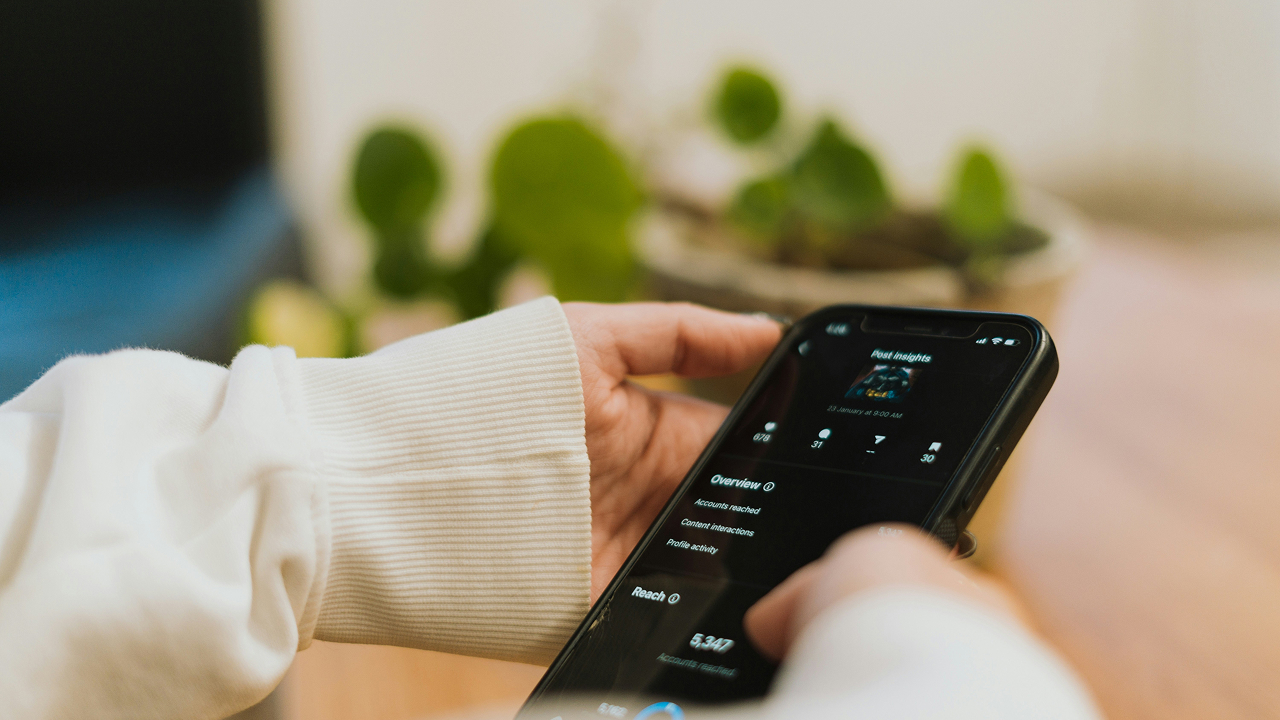 Hands holding a phone showing app insights, with plants in the background