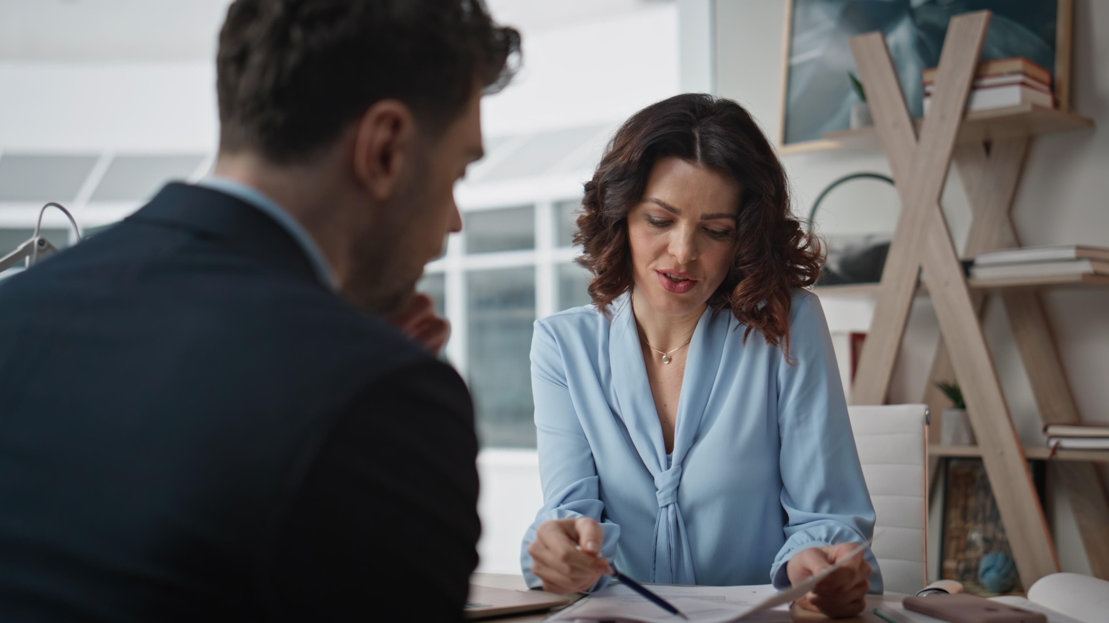 Two people talking at a desk and looking at a piece of paper