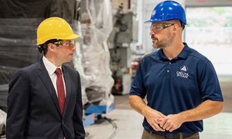 Keith Sonderling and a worker talking inside an industrial facility, both wearing hard hats