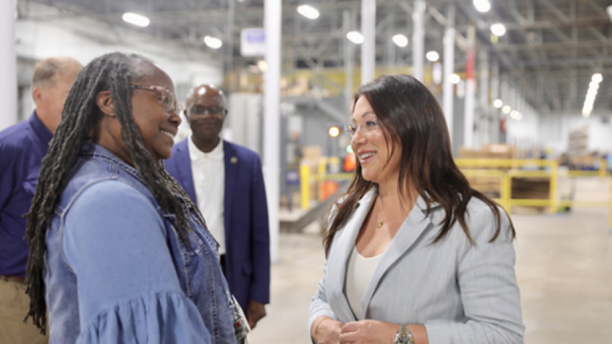 Secretary Lori Chavez-DeRemer speaking with a female worker in a warehouse-type workplace.