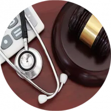 A calculator, stethoscope, and gavel on a desk.