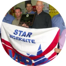Hendrickson employees hold a STAR worksite flag