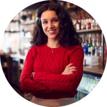 A female restaurant worker stands behind a bar counter