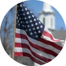 The U.S. flag with a church steeple visible in the background.