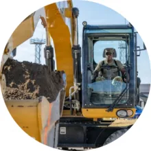 A service member drives an excavator