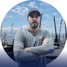 A man stands with his arms crossed in front of a dock