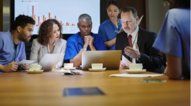 A group of people in a conference room looking at a laptop screen