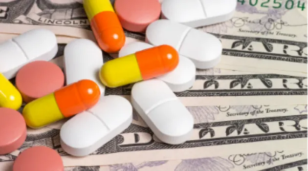 Medication in different pill forms resting on dollar bills