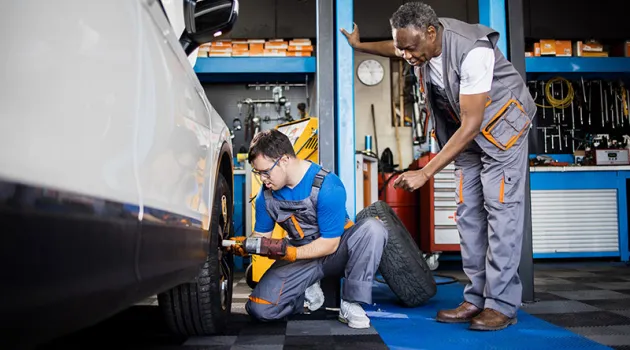 Apprentice and teacher working on a car in a bodyshop