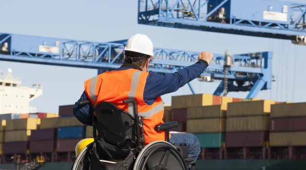 Man wearing an orange safety vest sitting in a wheelchair