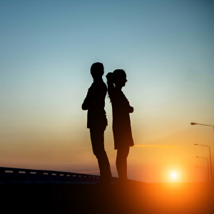 Silhouettes of two young people against the setting sun.