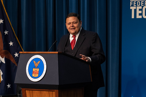 Labor Department Chief Information Officer Gundeep Ahluwalia speaks at a podium with the Labor Department seal. A banner behind her says Department of Labor Federal Tech Day 2023.