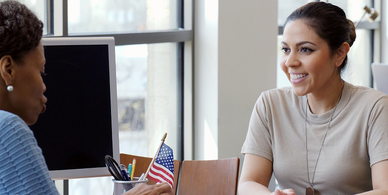 A female service member meets with a civilian woman in an office.