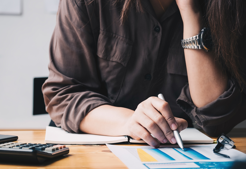 A woman sitting at a desk reviews a financial report