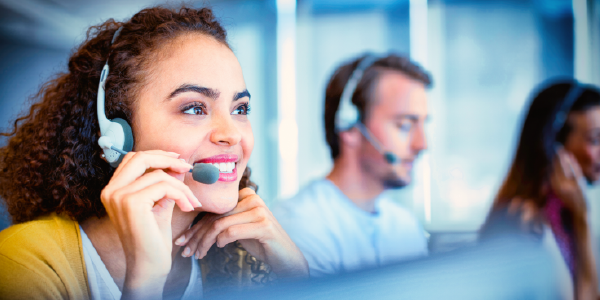 A woman wearing a headset smiles while working at a call center.