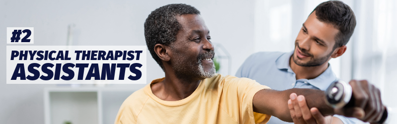 A younger man helps an older man with a physical therapy exercise involving a small hand weight. "Number 2: Physical therapist assistants"