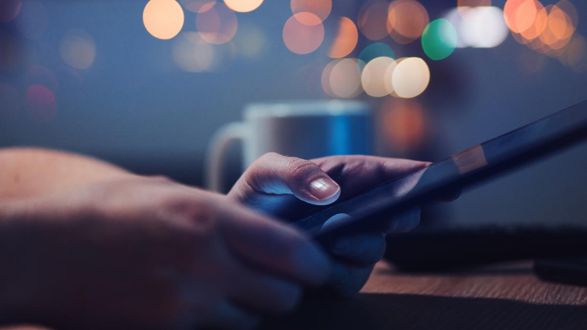 Close-up of hands holding a smartphone on a wooden table