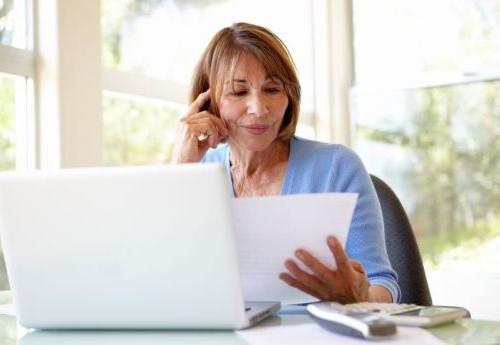 Woman sitting behind a computer and looking at a document.