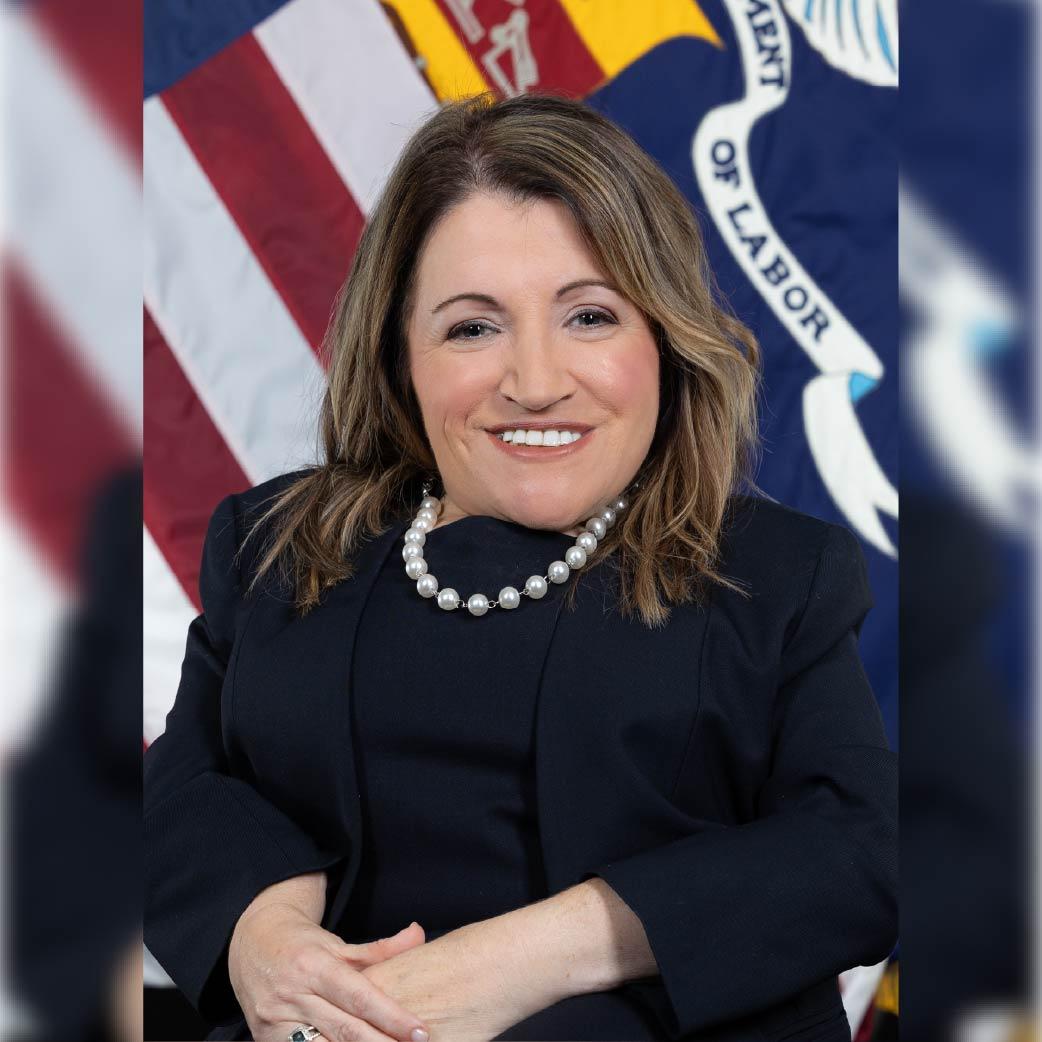 Professional headshot of Julie Hocker in front of the Labor Department flag