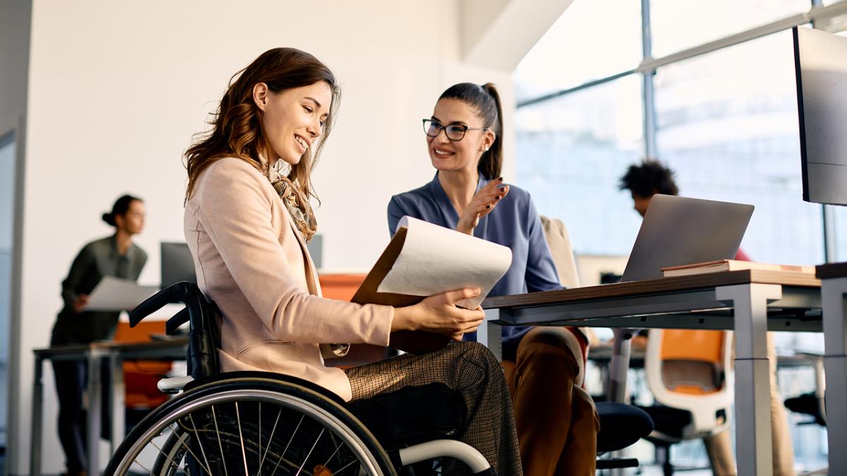 Happy disabled businesswoman and her colleague cooperating while working in the office