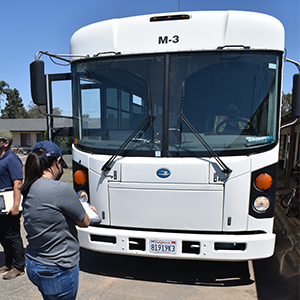 Person with clipboard in front of unoccupied labor bus