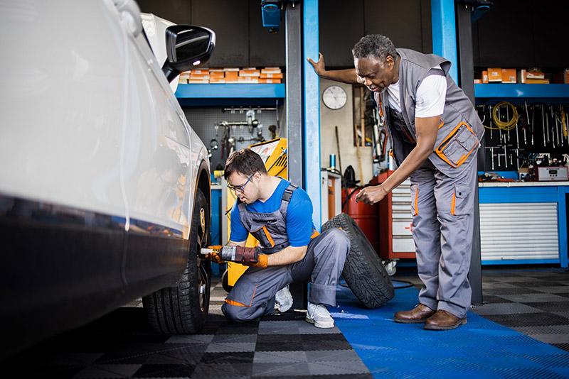 Apprentice and teacher working on a car in a bodyshop