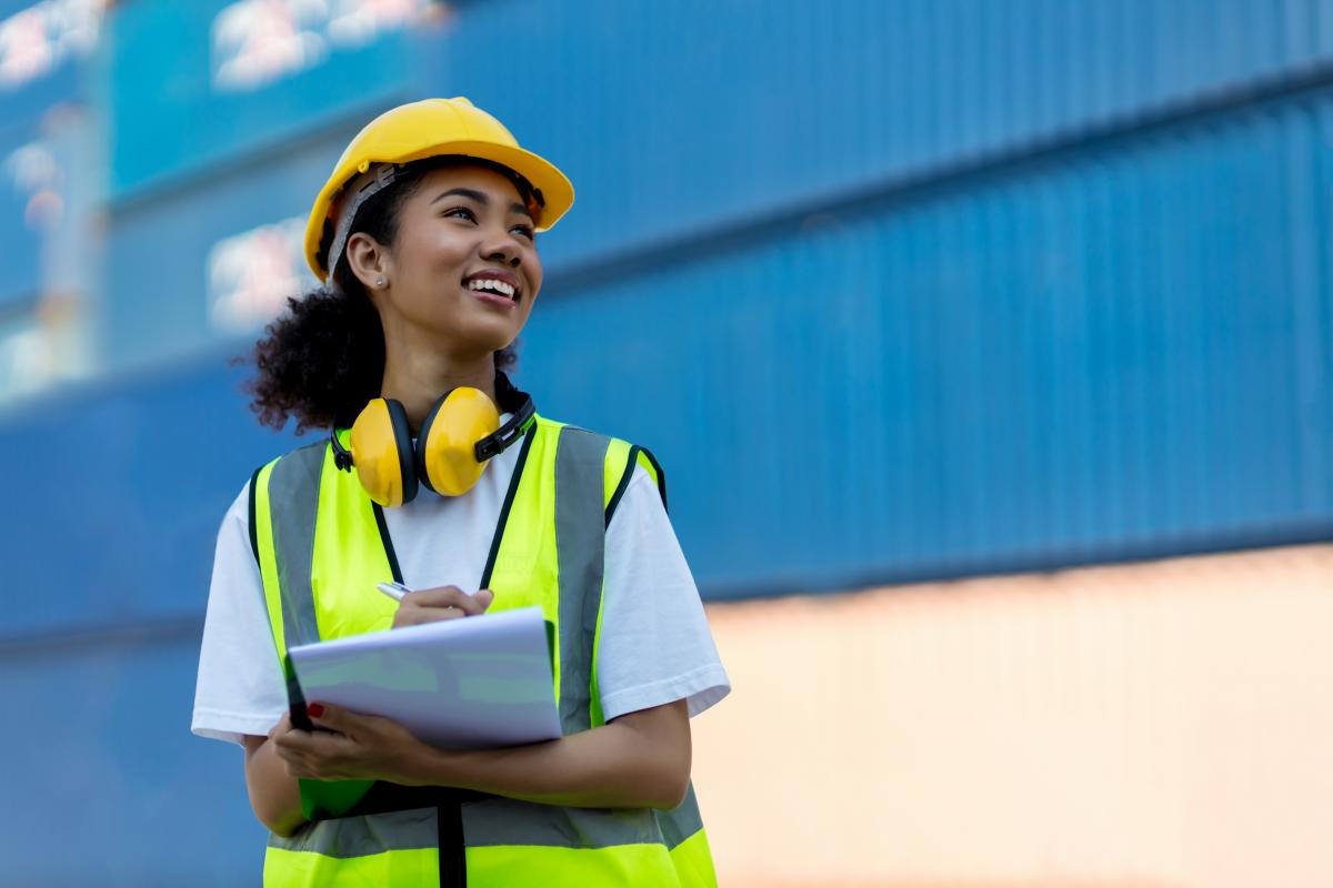 A woman wearing a yellow safety vest and holding a clipboard
