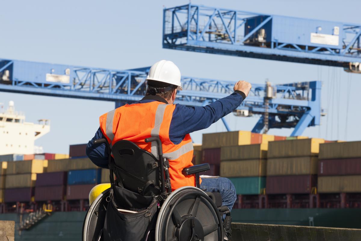 Man wearing an orange safety vest sitting in a wheelchair