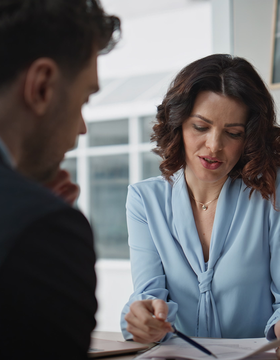 Two people talking at a desk and looking at a piece of paper